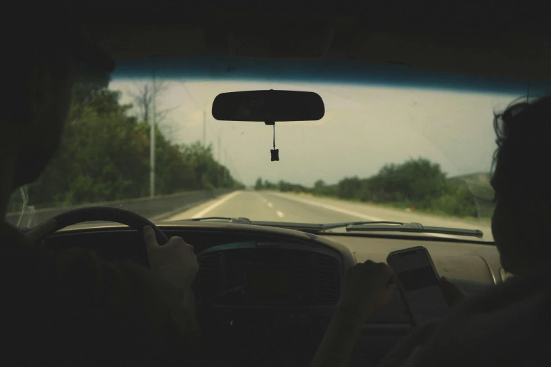 a person holding their cell phone while driving in a car