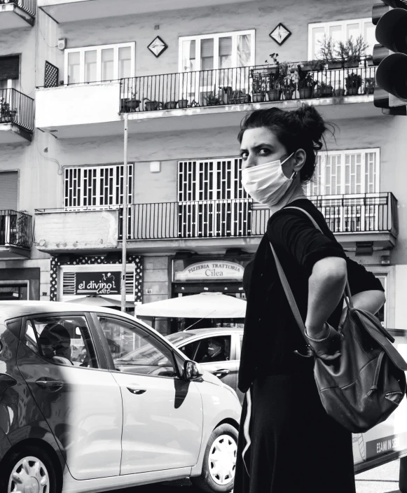 a woman in a mask walking next to a car