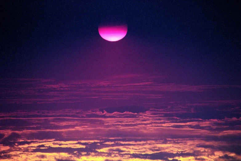 the bright orange glowing moon seen through a purple sky