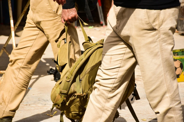 two persons walking side by side carrying a bag