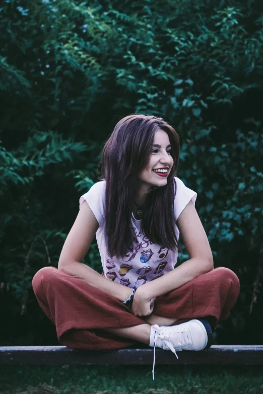 a smiling girl sitting on a bench outdoors