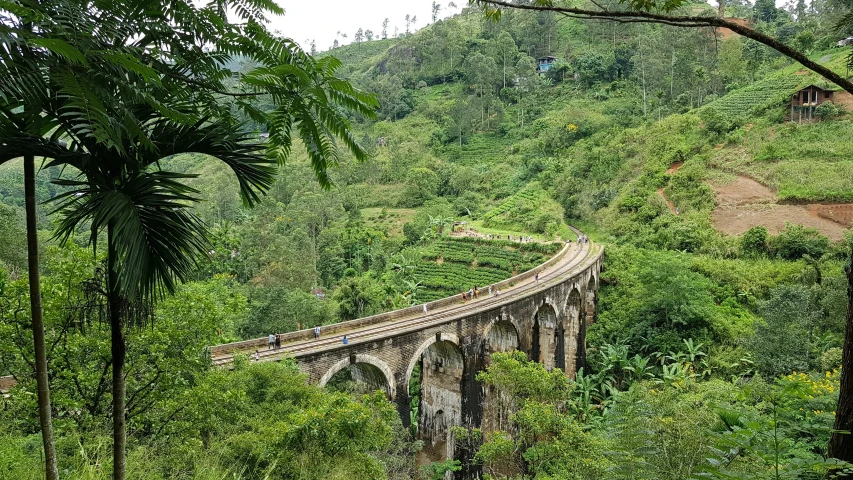 an old bridge is surrounded by trees and hills