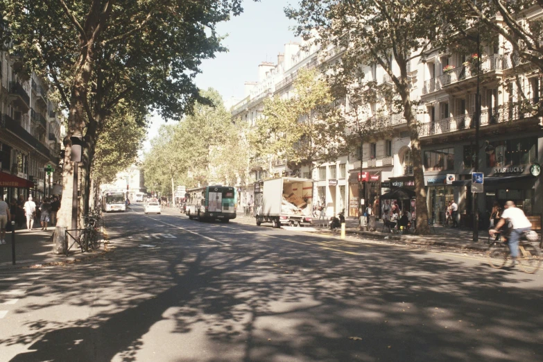 a street with several vehicles, a man on a bike, and pedestrians