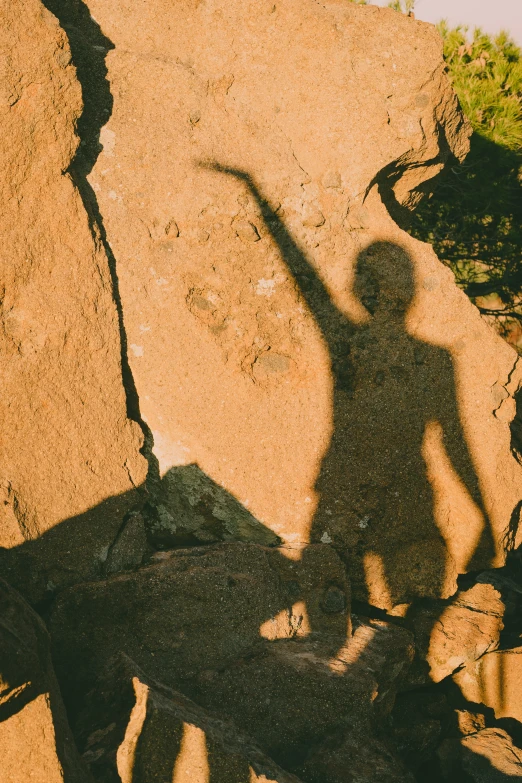 a shadow of a man who is standing near some rocks