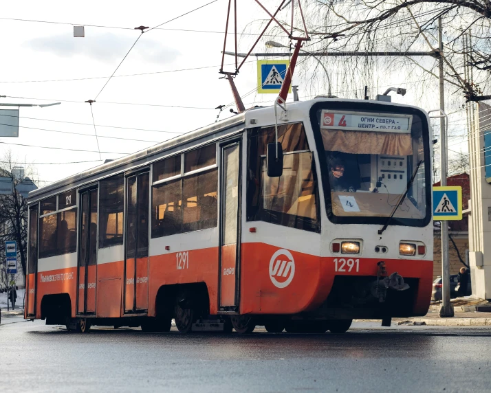 an orange and white bus driving down a street
