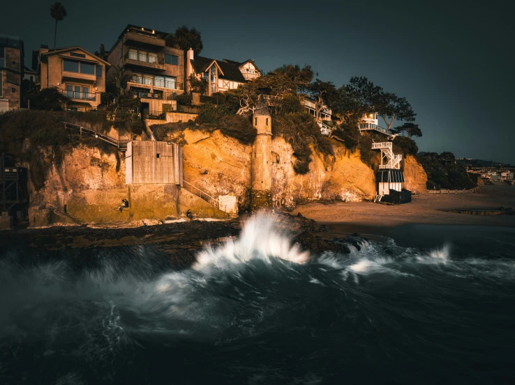 houses on cliffs overlooking ocean with crashing waves