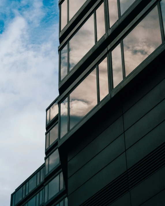 a tall glass building and the sky reflected in it