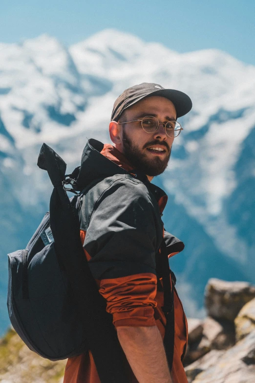 man with beard and glasses with large backpack on top of mountain