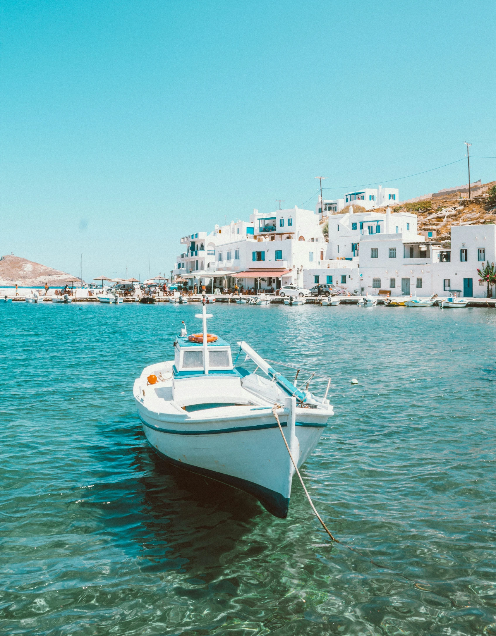 a small boat anchored in the water near white buildings