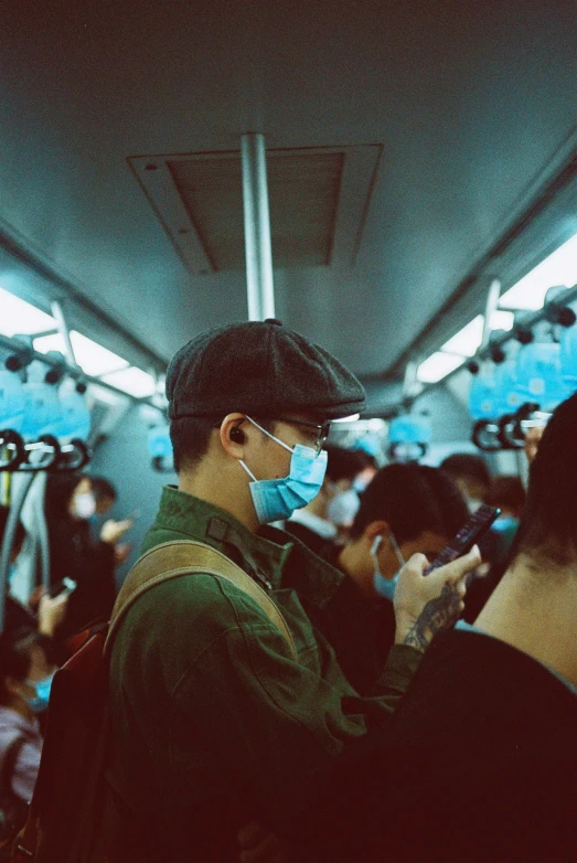 a man on a train wearing a face mask and looking at his phone