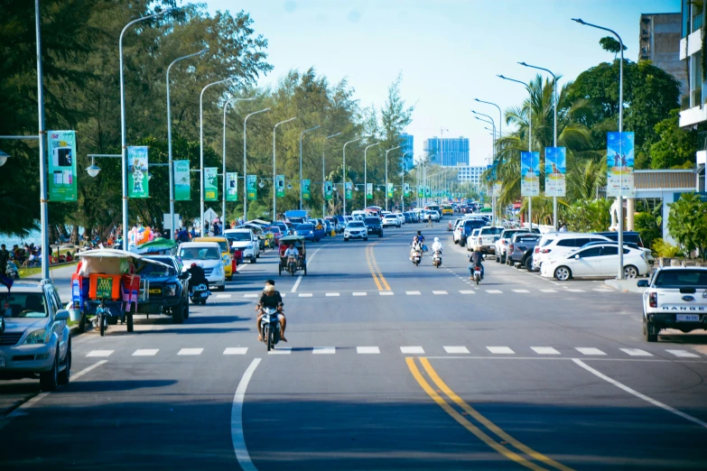 a large amount of motorcyclists and cars are driving down a street