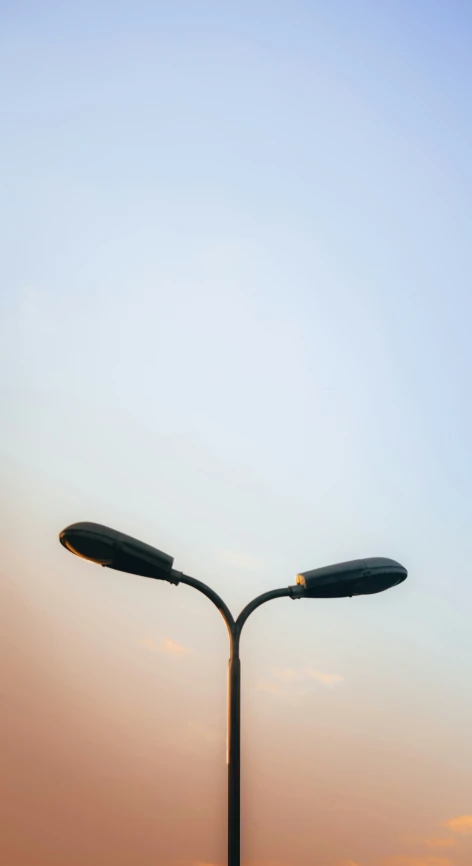 a street light is standing at sunset on the corner of a street