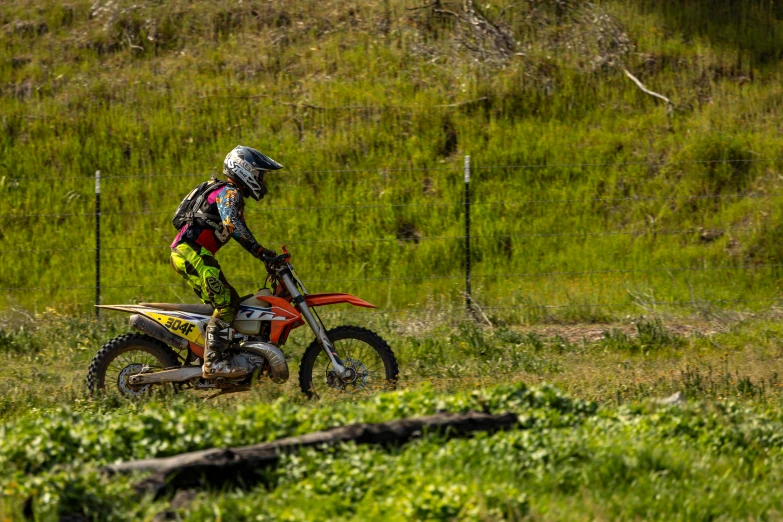 a dirt bike rider dressed in motorcycle gear rides through the grass