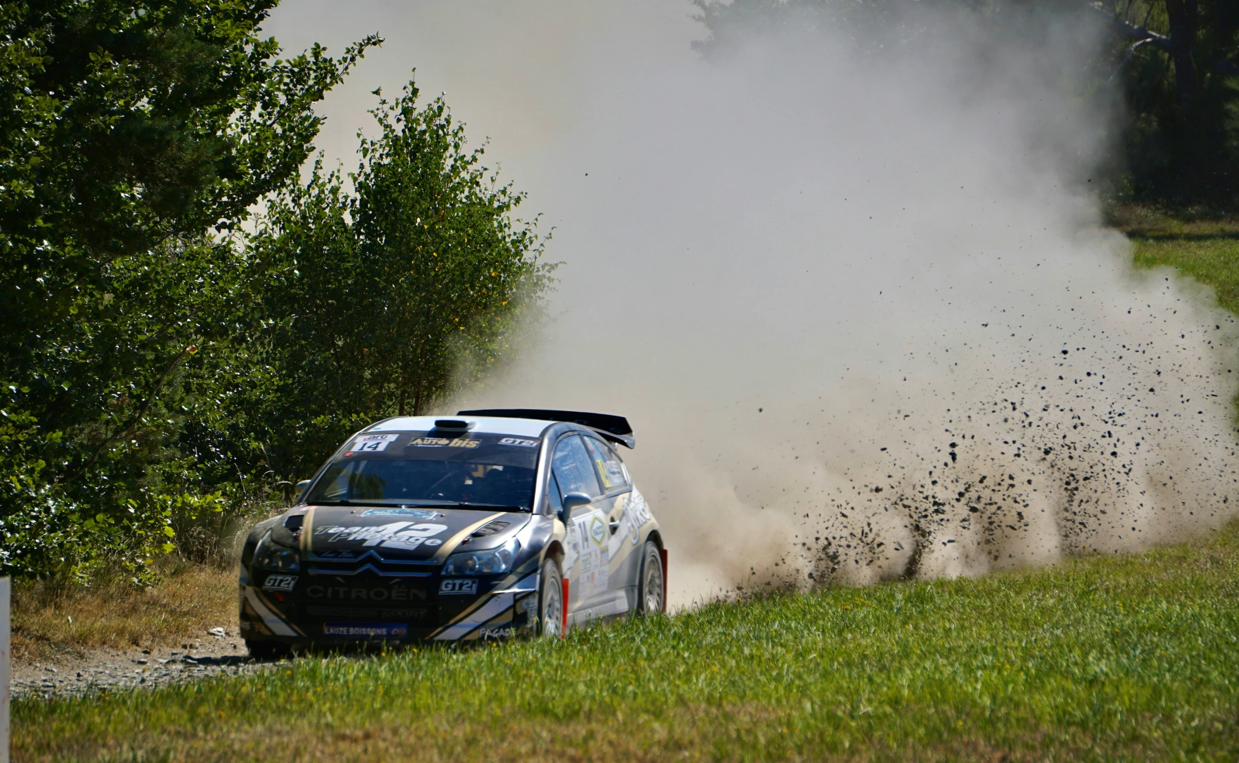 a rally car kicking up dirt on the race course