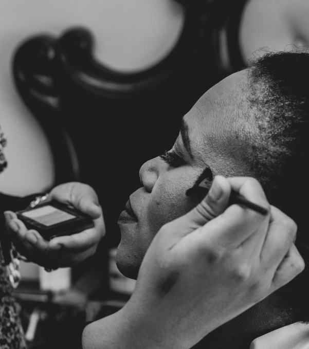 a woman with a hairdo is sitting and applying her lipstick