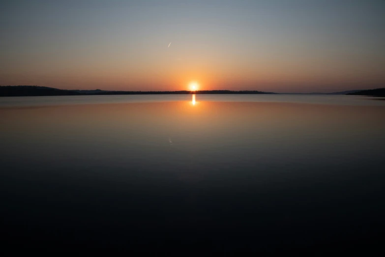 the sun is setting over the water as seen from a boat