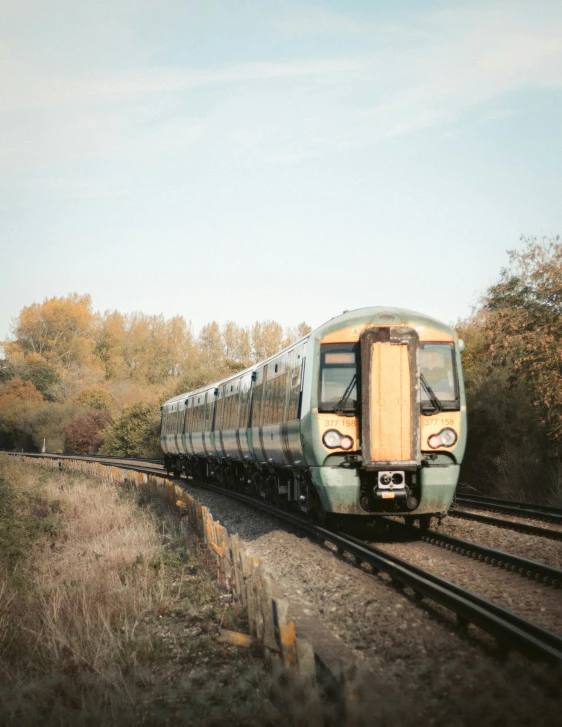 a commuter train on the tracks with trees in background