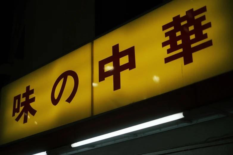 a yellow sign with asian writing and some lights