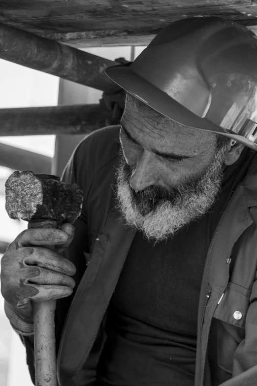 a man with a beard wearing a hard hat looking at a piece of meat