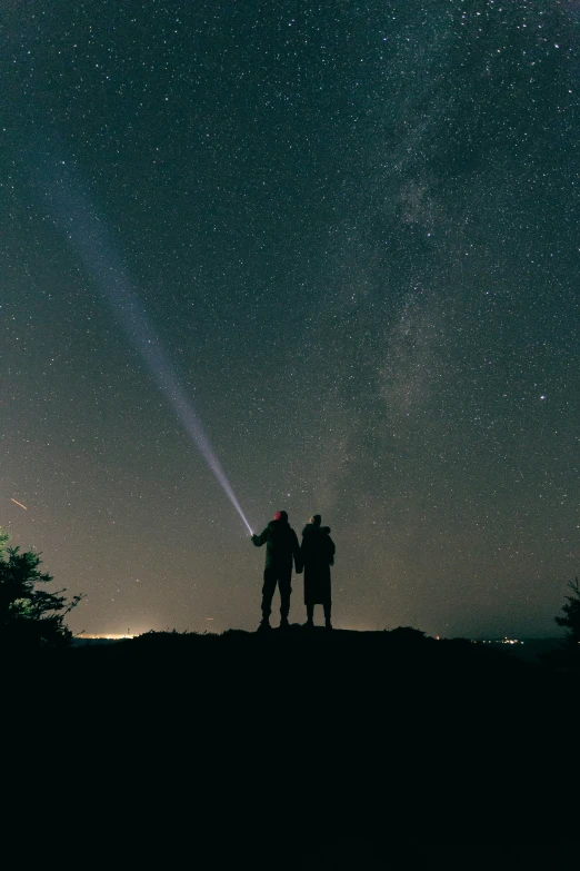 two people standing in front of the night sky with their arms around each other