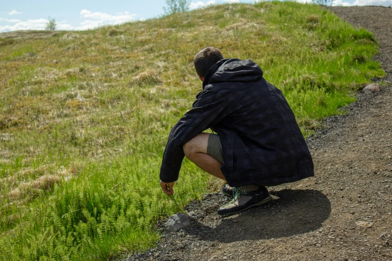 the man is leaning over on the grassy hill