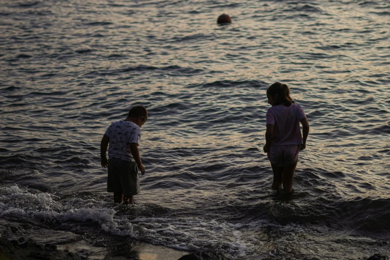 two young people standing in water on beach