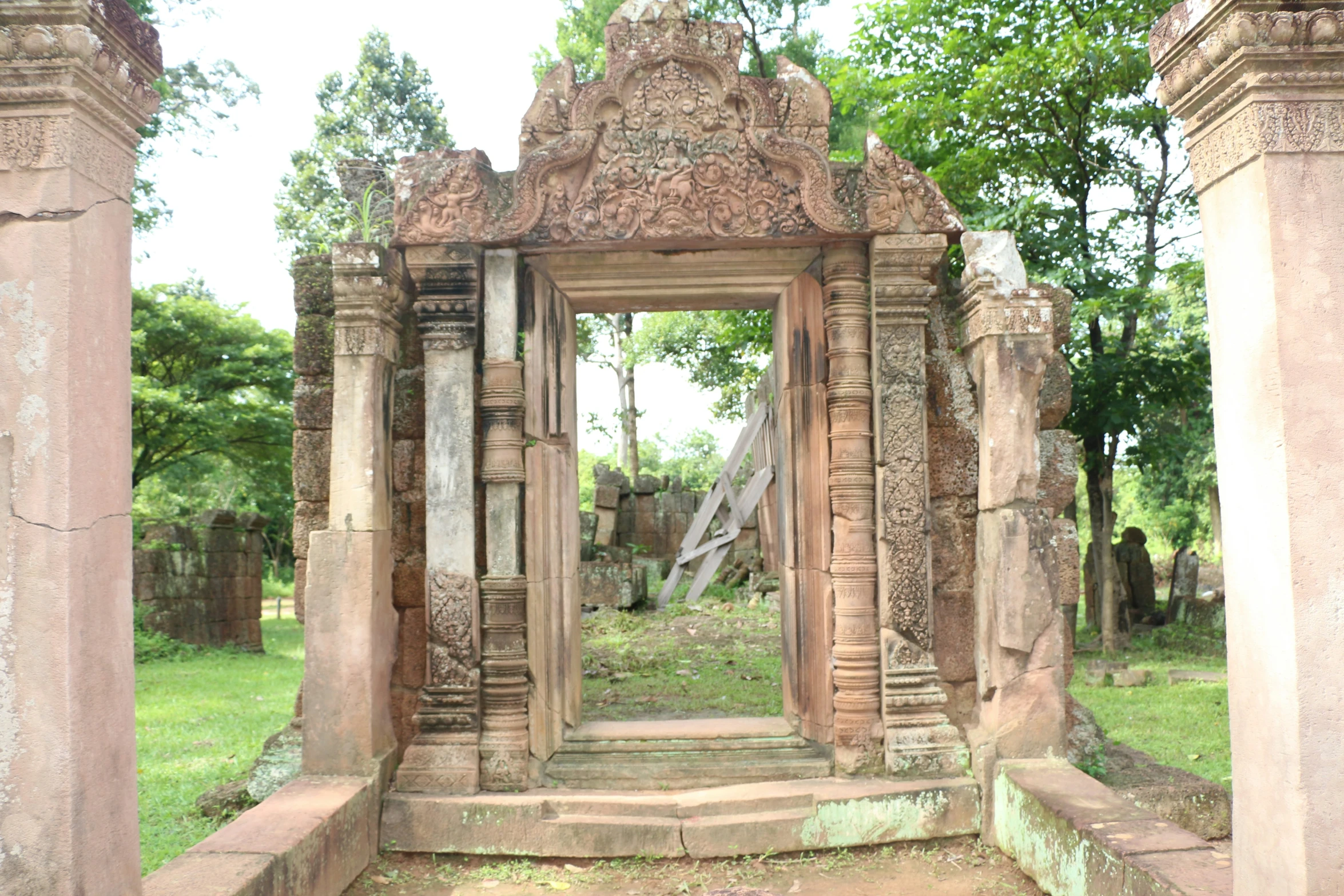 an ancient entrance way to a cemetery next to trees