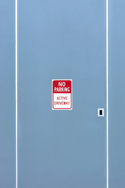 a red and white sign stating no parking on a gray wall