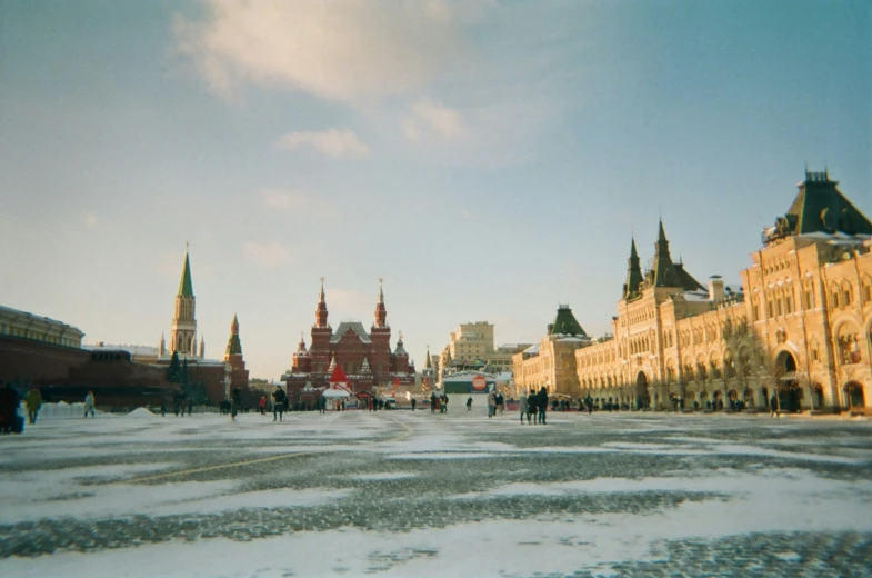 a group of people walk through the snow next to some buildings