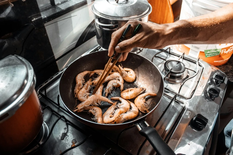 a man cooking food with his hands on a stove