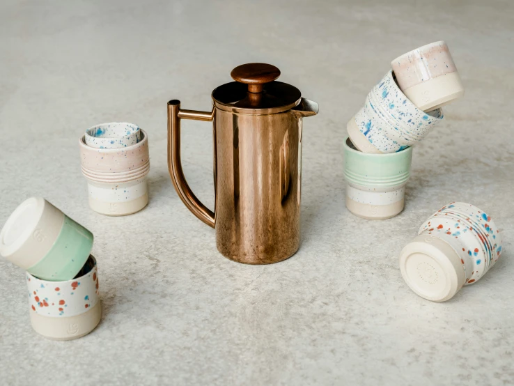 a metal coffee pot with five cups on top