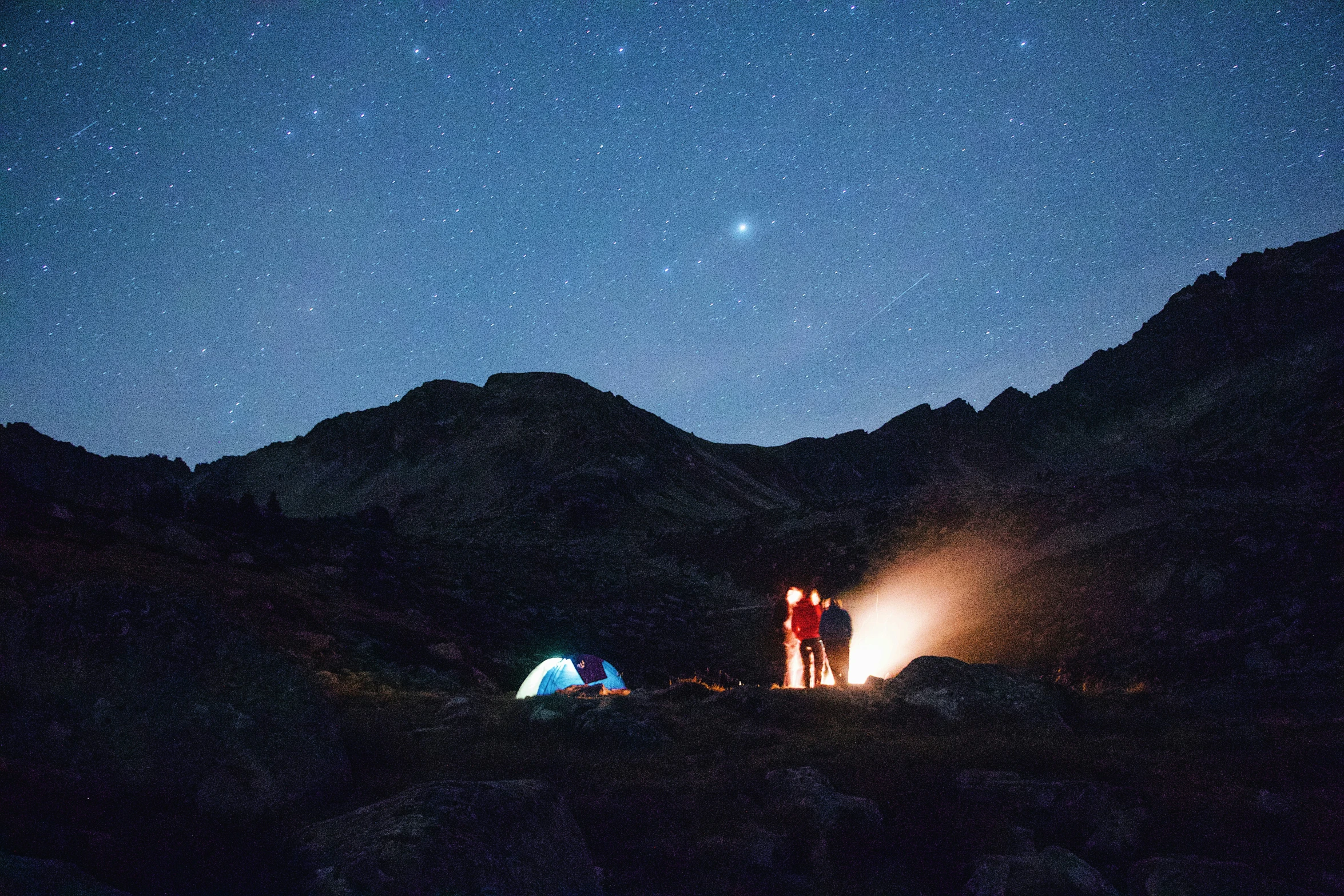 two people standing near camping equipment at night