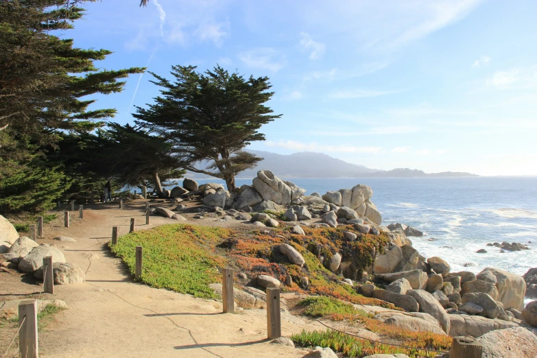 a path that leads to a beach next to some water