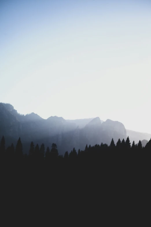 a dark po of mountains and trees at sunset