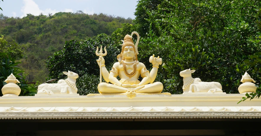 a statue sitting in a park near a forest