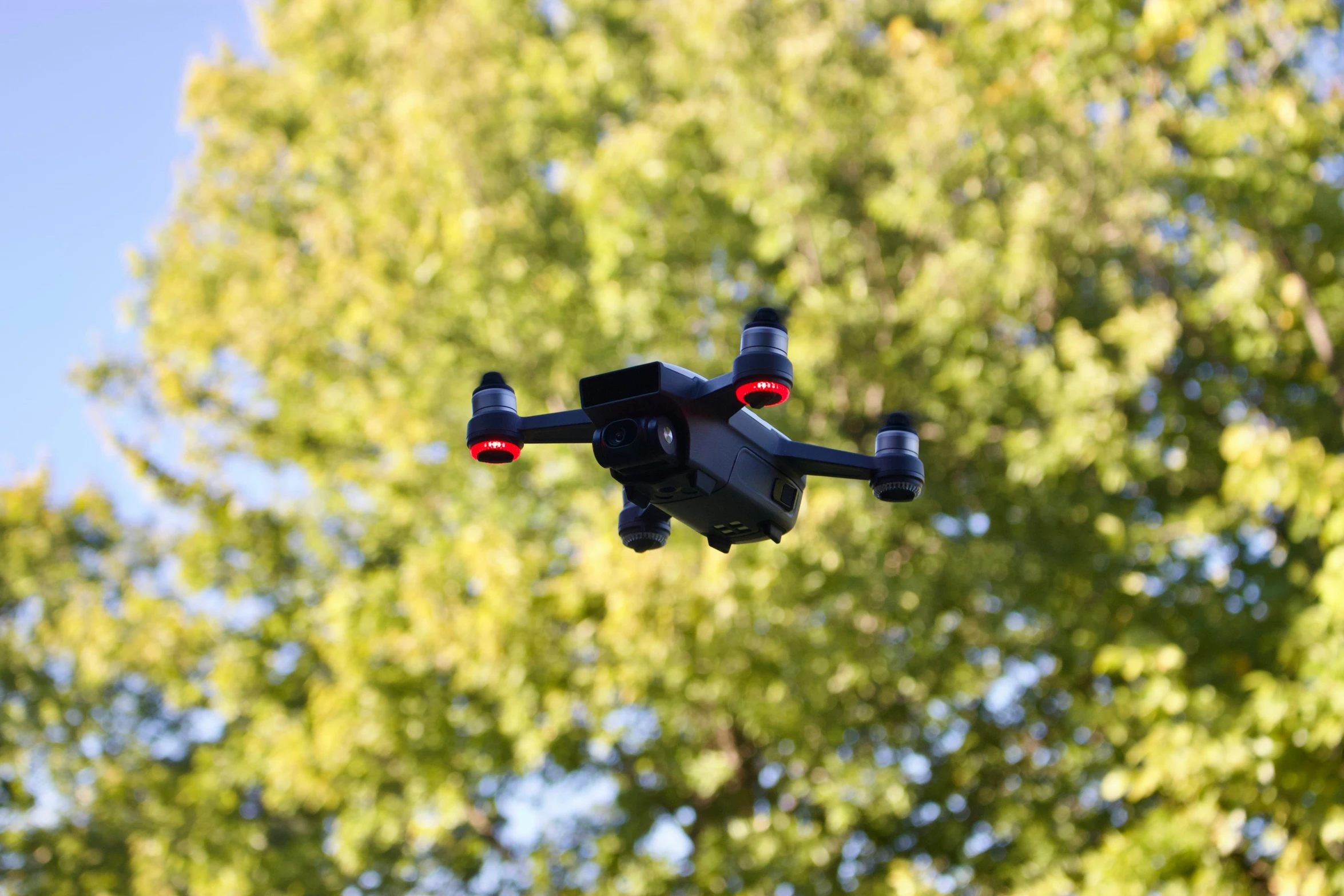 a remote controlled airplane in the sky with trees in the background