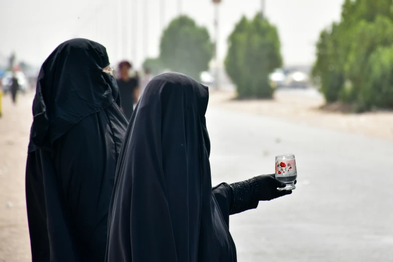 two women in black holding up some cans