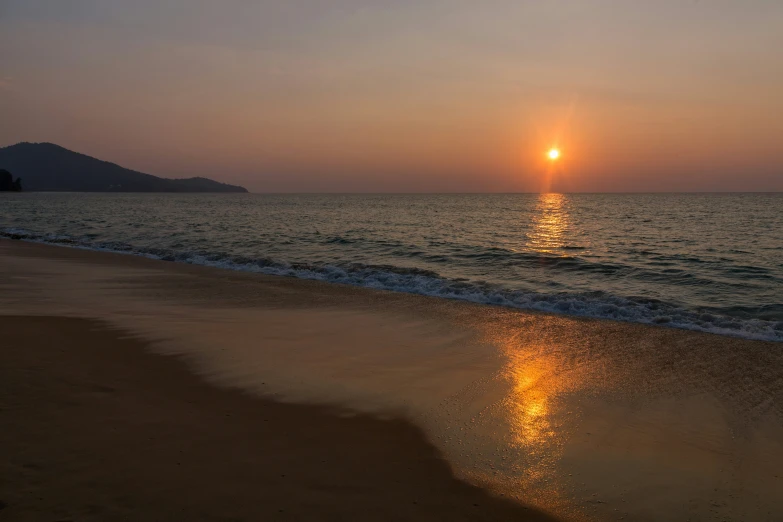 the sun is setting over the beach as waves come in