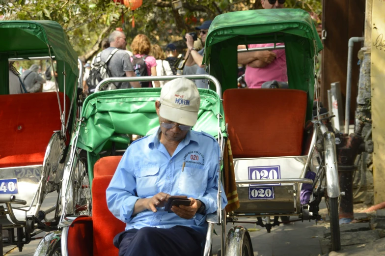 a man in a blue shirt and white hat sitting in the middle of two carriages