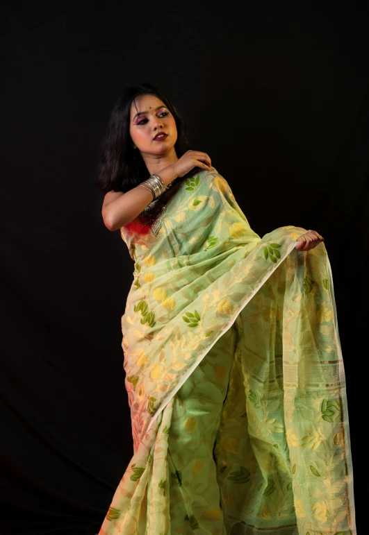 a woman in yellow and green saree posing with her arms crossed