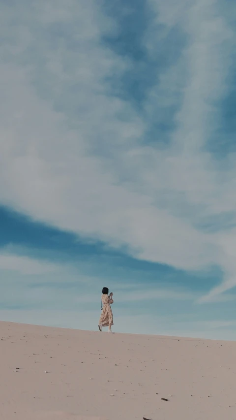 two people flying a kite on top of a sandy hill