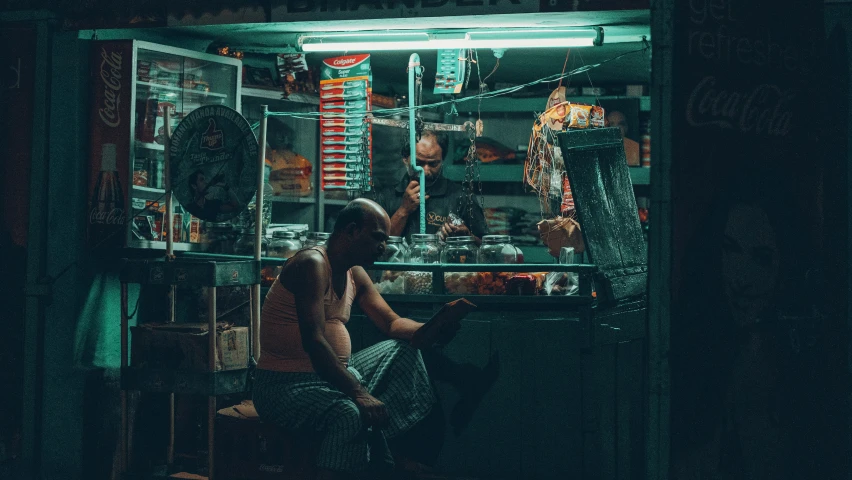 a man sitting in the window of a shop at night