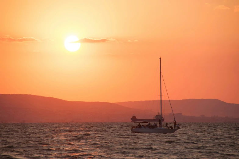 the sun setting behind a boat in the ocean