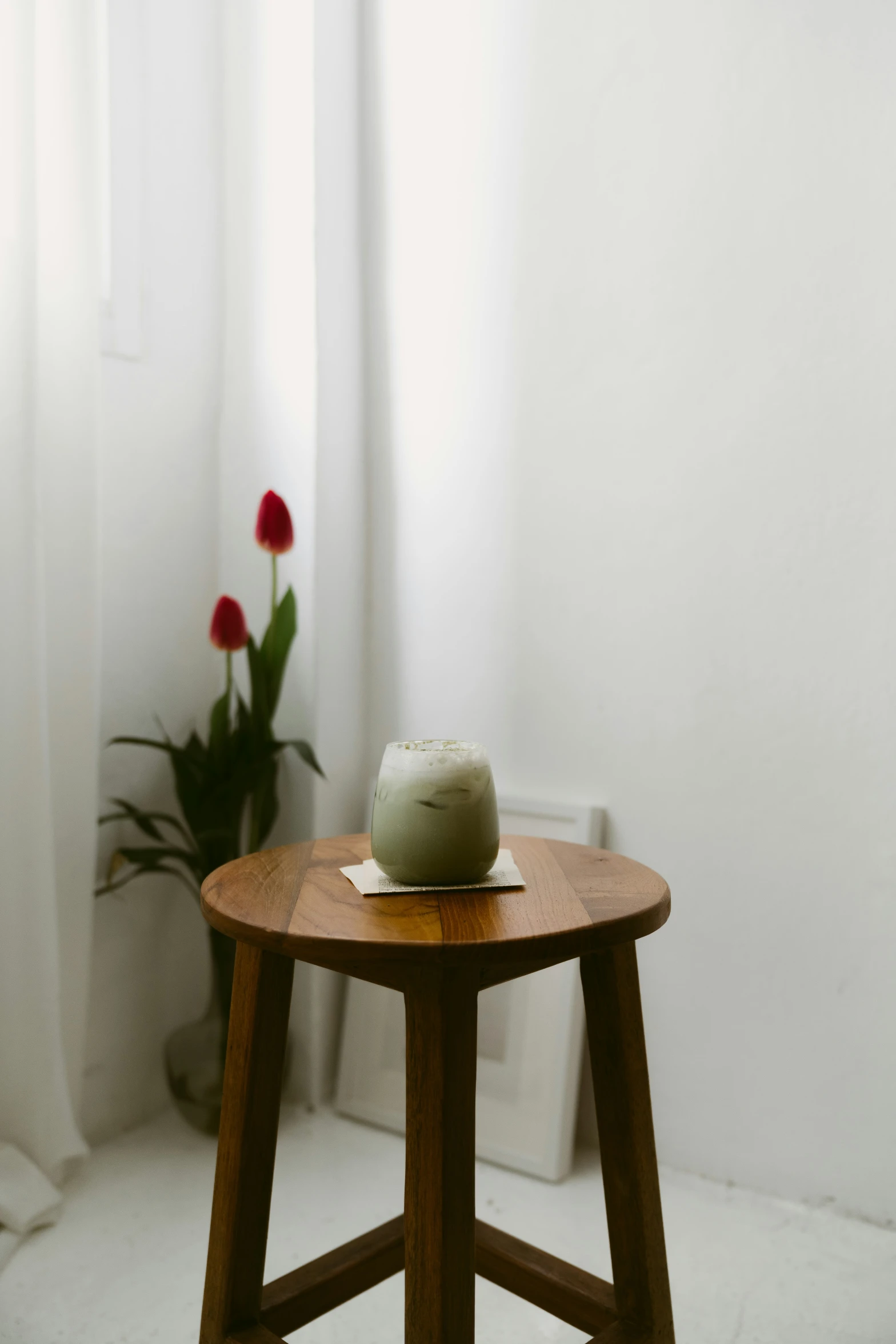 a small table with flowers on it in front of the curtain