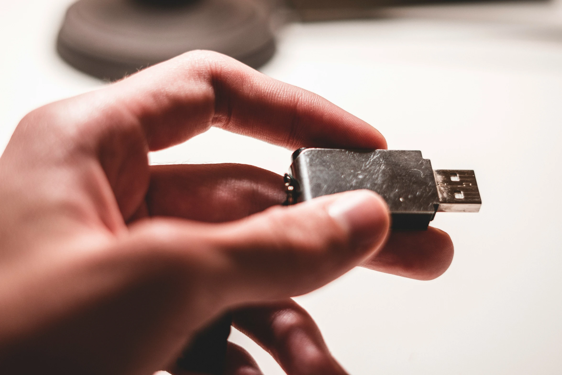 a hand holding a tiny metal object with white keys