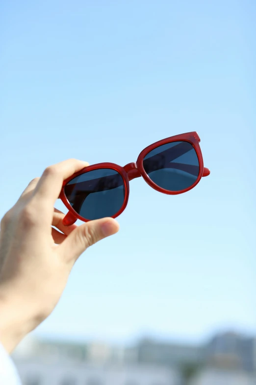 a woman is holding on to some sunglasses in her hand