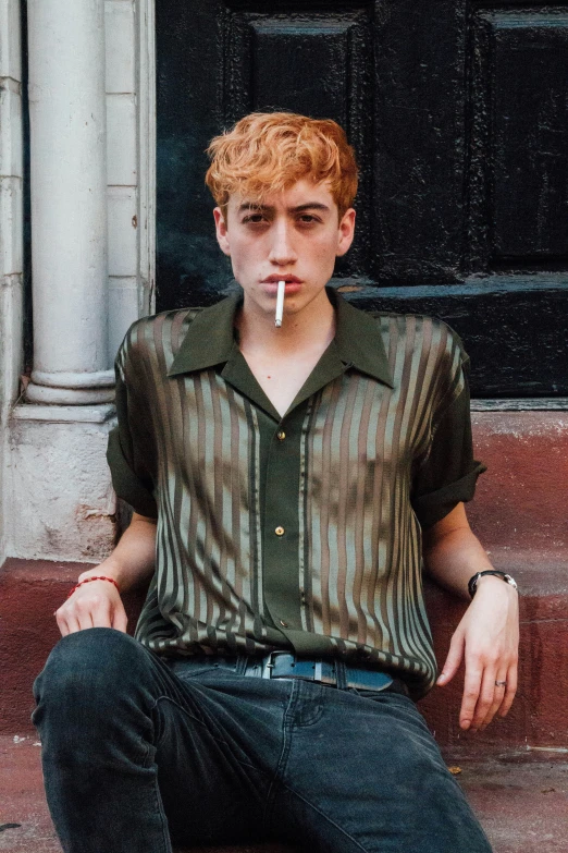 a boy smokes a cigarette while sitting on the steps of an old building