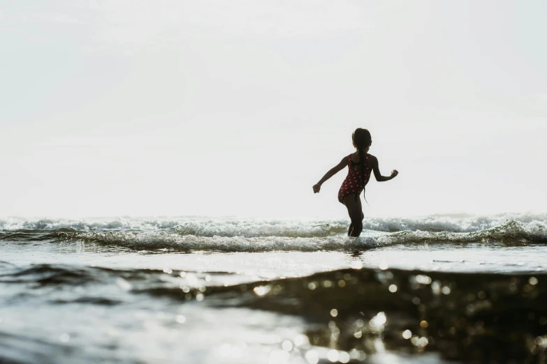 a girl in red is running through the water