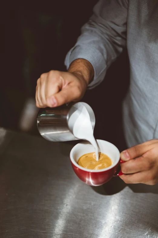 a person pouring sugar into a cup with another hand and spoon