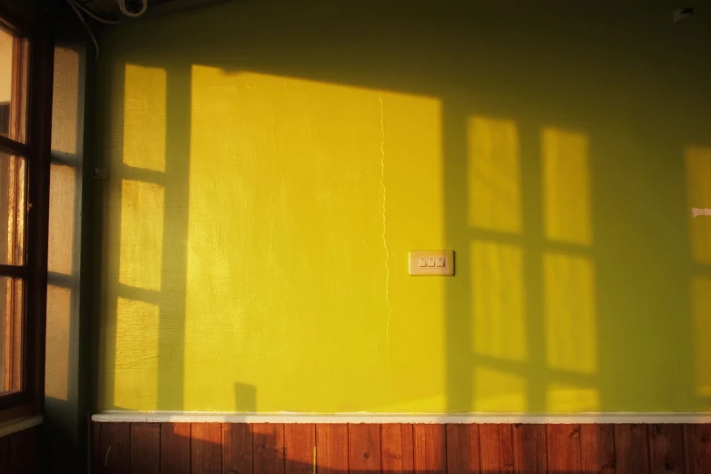 a small window on a green wall by some wooden paneling